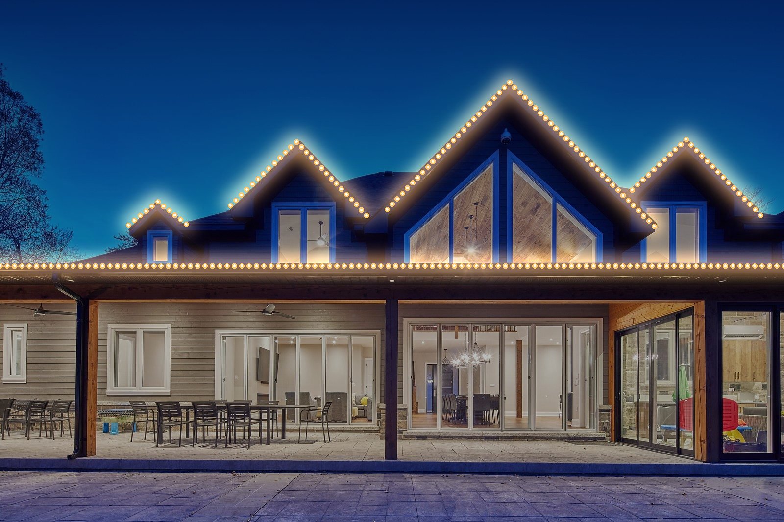 Large gabled home with warm white permanent roofline lights (lights added digitally)