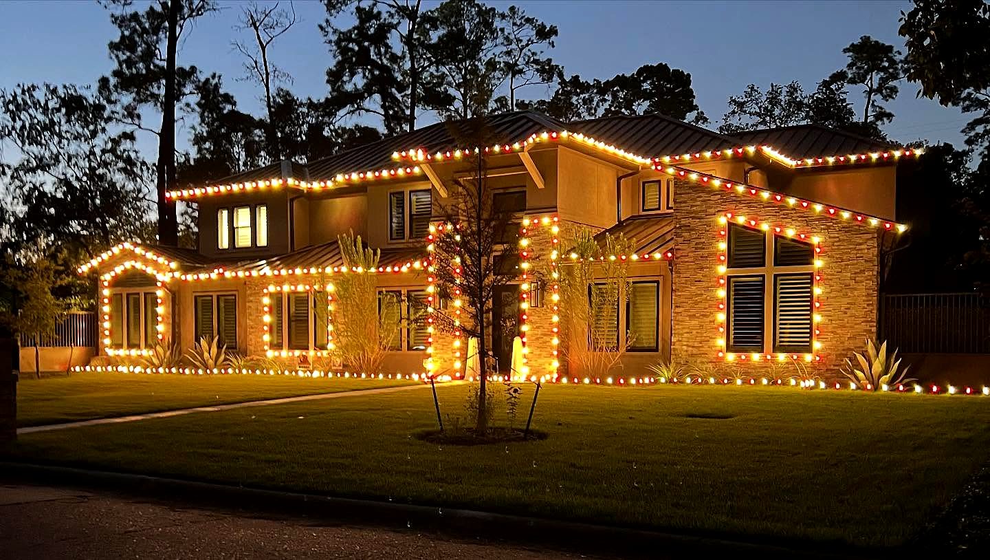 Texas Beam install: two-story home outlined in warm white lights at dusk